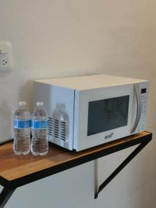 a microwave and two bottles of water on a shelf at La casita del árbol, amplia y cómoda en barrio familiar in Campeche