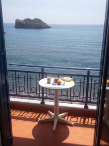 a table on a balcony with a view of the ocean at Hotel Kyma in Skala Eresou