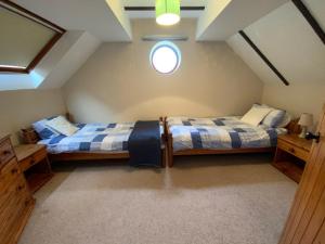 a attic bedroom with two beds and a window at Sherbourne Cottage, Seven Springs Cottages in Cheltenham