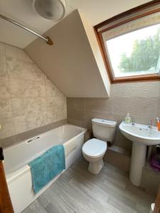 a bathroom with a white tub and a toilet and a sink at Sherbourne Cottage, Seven Springs Cottages in Cheltenham