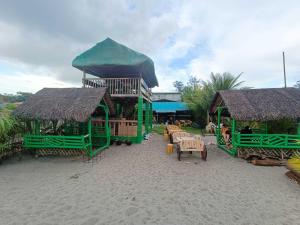 a building on the beach with tables and chairs at Mope Beach Resort in San Narciso