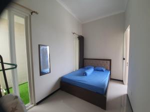 Villa Bahari Batu في باتو: غرفة نوم بسرير وملاءات زرقاء ونافذة