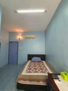 a bedroom with a bed and a blue wall at Deummah Guest Room in Cukai