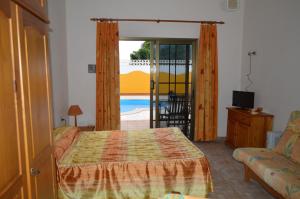 ein Schlafzimmer mit einem Bett und einer Glasschiebetür in der Unterkunft Casa la Ermita in Máguez