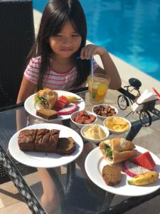 a little girl sitting at a table with plates of food at Palma Resort Phu Quoc, Trademark Collection by Wyndham in Phú Quốc