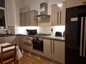 a kitchen with white cabinets and a stove top oven at Bright 3 Bedroom Edinburgh City Apt in Edinburgh
