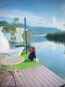 a woman sitting on the grass next to a lake at เขาเจ้าขา2 in Khao Kho