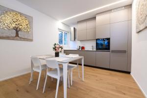 cocina y comedor con mesa blanca y sillas en Lake Modern Suites - Free Parking, en Lugano