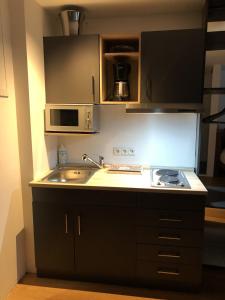 a kitchen with a sink and a stove and a microwave at Appartement Wettersteinblick in Seefeld in Tirol