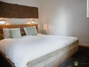 um quarto com uma cama de madeira com lençóis e almofadas brancos em Vibrant Farmhouse near Forest in Heeze-Leende em Leende