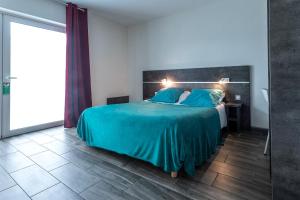 a bedroom with a bed with blue sheets and a mirror at Hôtel de la Gare in Surgères