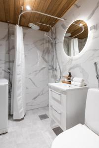 a white bathroom with a shower and a sink at Arctic Night City Suite in Rovaniemi