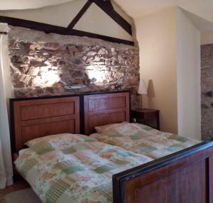 1 dormitorio con cama y pared de piedra en Moulin des Vernes, en Ouroux