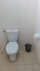 a bathroom with a white toilet and a trash can at PURNAMA HOUSE KUTA in Kuta