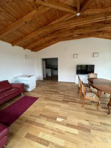 sala de estar con techo de madera, mesa y sillas en Pannonia Appartements, en Bad Tatzmannsdorf