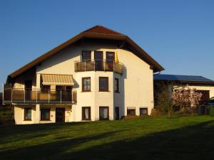 a large white building with balconies on a grass field at Schmidt`s Eppelborner Ferienwohnung in Eppelborn