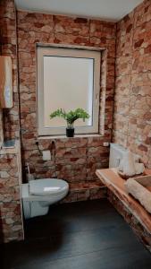 a bathroom with a brick wall with a toilet and a window at Love Cottage mit Whirlpool in Hagen
