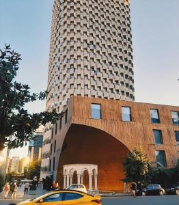 un taxi jaune garé devant un grand bâtiment dans l'établissement LAIOLA APARTMENT, à Tirana