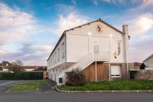 a white building with a staircase on the side of it at Hôtel de la Gare in Surgères