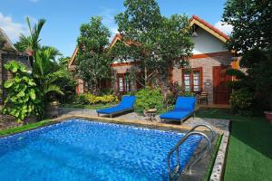a swimming pool with two blue chairs next to a house at Tamcoc Mr. Cau Homestay in Ninh Binh