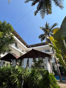 a large building with an umbrella and palm trees at La Vera Boutique Hotel, Mandrem in Mandrem