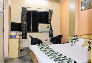 Zimmer mit einem Bett und einem Fenster mit Stühlen in der Unterkunft Maruti Group of Hotels - Shree Ram Darshan in Nāthdwāra