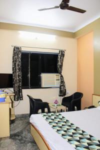 Cette chambre comprend un lit, des chaises et une fenêtre. dans l'établissement Maruti Group of Hotels - Shree Ram Darshan, à Nathdwara