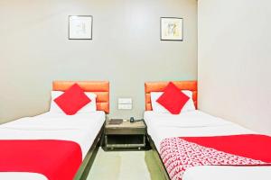 Hotel Amfahh - Andheri West Railway Station في مومباي: سريرين في غرفة مع وسائد حمراء