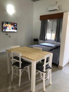 una mesa de madera y sillas en una habitación con cama en Calido y centrico monoambiente en Concordia