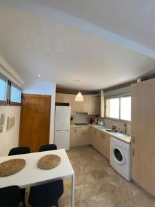 een keuken met een tafel en een wasmachine bij 2 Bedrooms and sofa bed flat by Wayra Tarifa in Tarifa +5 foto's