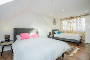 una camera con 2 letti con cuscini rosa di Entire Lovely family home with Wi-Fi, Netflix, self check-in a Londra
