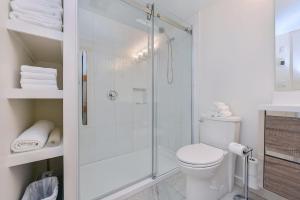 a white bathroom with a shower and a toilet at Bazan Bay Beach House in North Saanich