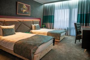 a hotel room with two beds and a desk at Park Hotel Green Europe in Haskovo