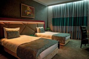 a hotel room with two beds and a chair at Park Hotel Green Europe in Haskovo