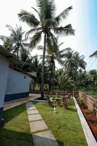 a garden with chairs and a palm tree at The Little Prince - Mangalore Beach Homestay in Mangalore