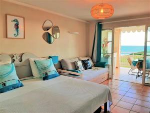 a bedroom with a bed and a living room at STUDIO CARAMBOLE VUE MER - Piscines - Plages - Village vacances Sainte Anne Guadeloupe in Sainte-Anne