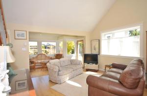 sala de estar con sofá, sillas y TV en Heron View Cottage en Sidney
