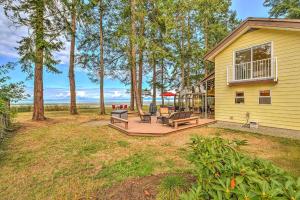 a backyard with a deck with benches and trees at Kye Bay Beach House in Comox