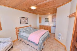 a small bedroom with a bed and a kitchen at Kye Bay Beach House in Comox