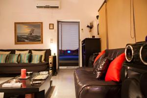 een woonkamer met twee leren banken en een tafel bij Frangipani Penthouse in New Delhi