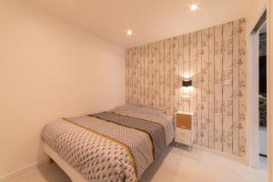 a small bedroom with a bed and a wall at LE ROYAL SWEET - PARKING GRATUIT + WIFI in Mulhouse