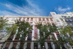 un bâtiment rose et blanc avec des arbres devant lui dans l'établissement Fee4Me Vallés 6, à Madrid