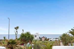 a white house with palm trees in front of the ocean at Seaview at No. 26 Northumberland Place in Teignmouth