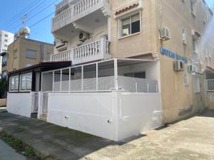 een gebouw met een wit hek ervoor bij Kontheo Elli Ground Apt 2 near the beach in Larnaka