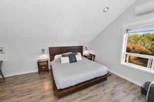 a white bedroom with a bed and a window at Falcon Suite in Cowichan Bay