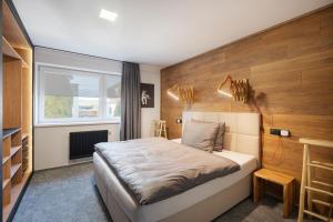 een slaapkamer met een bed met een houten muur bij APARTMANY L&O - Oliver in Zvolenské Nemce