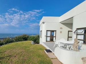 a white house with a table and a view of the ocean at Angel's Rest in Port Alfred