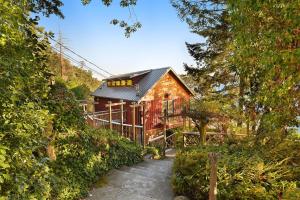 a wooden cabin with a black roof in a forest at Salishan Tree House Suite in Cowichan Bay