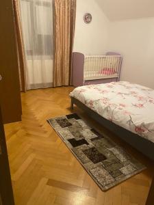 a bedroom with a bed and a rug on a wooden floor at Vila primitoare in apropiere de aeroport in Ghiroda