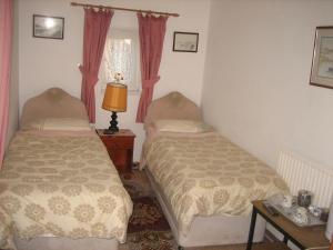 a bedroom with two beds and a table with a lamp at Four seasons Guest House in Pembrey
